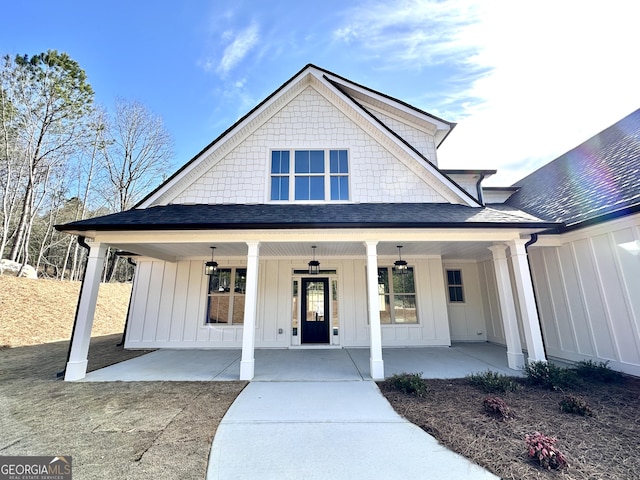 view of front of house with board and batten siding, roof with shingles, and a porch