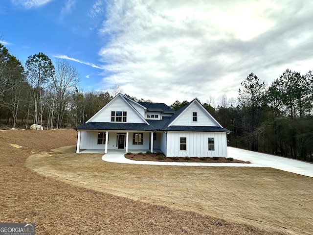 modern farmhouse with a porch, board and batten siding, and roof with shingles