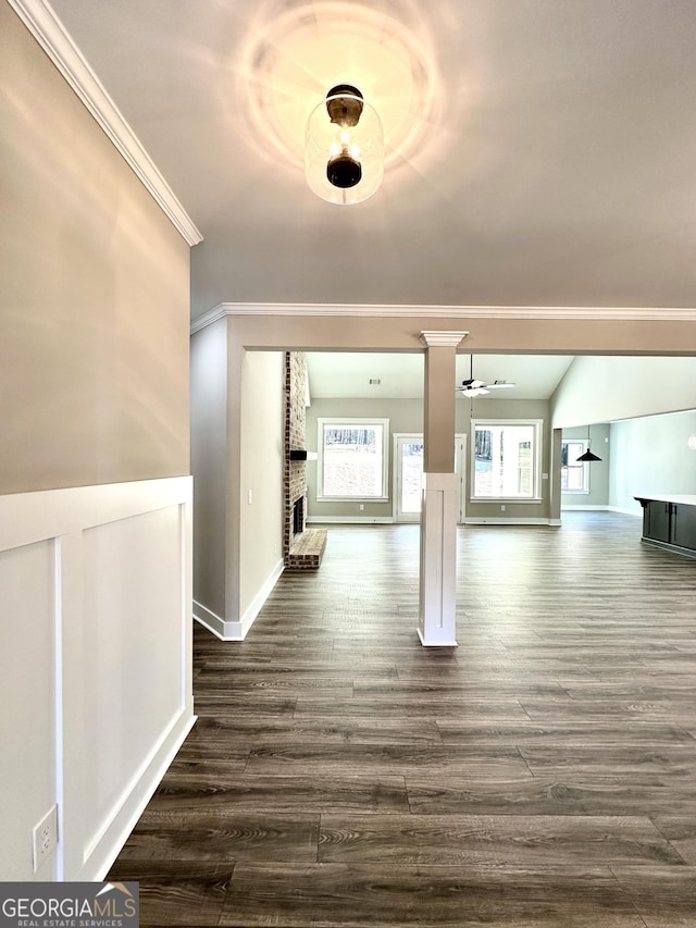 corridor with baseboards, decorative columns, ornamental molding, and dark wood-style flooring