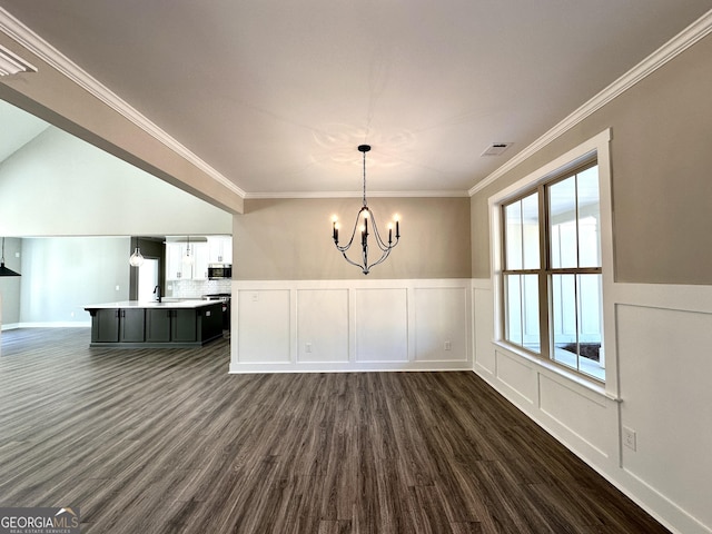 unfurnished dining area featuring visible vents, dark wood-style flooring, crown molding, a chandelier, and a decorative wall