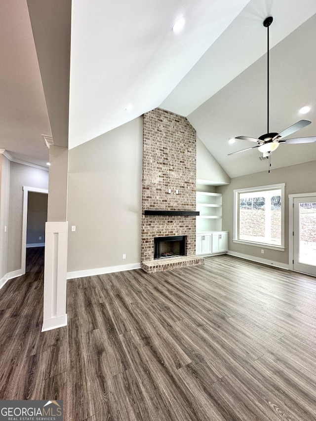 unfurnished living room featuring baseboards, ceiling fan, wood finished floors, vaulted ceiling, and a brick fireplace