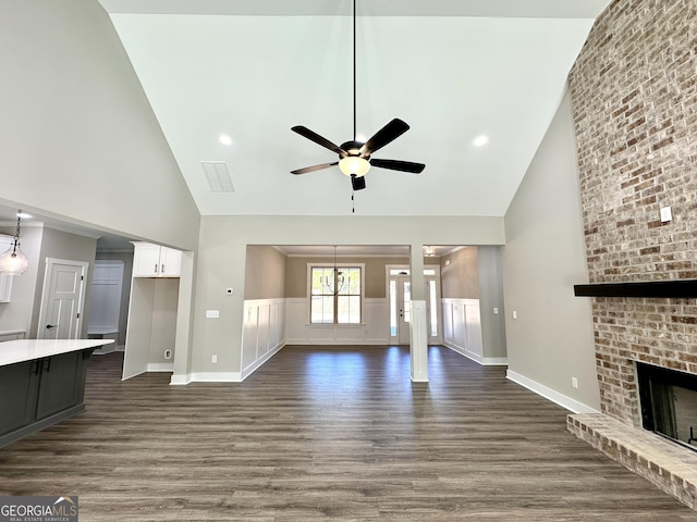 unfurnished living room featuring high vaulted ceiling, a fireplace, dark wood finished floors, and a ceiling fan