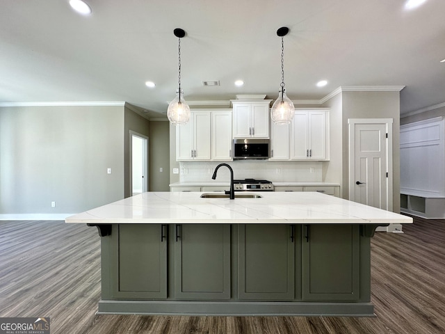 kitchen featuring a spacious island, a sink, white cabinetry, stainless steel microwave, and dark wood finished floors