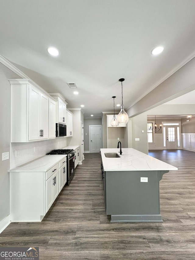 kitchen with a sink, ornamental molding, dark wood-style floors, an island with sink, and stainless steel range with gas stovetop