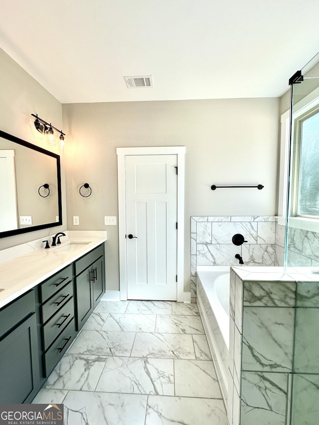 bathroom with marble finish floor, double vanity, visible vents, a sink, and a bath