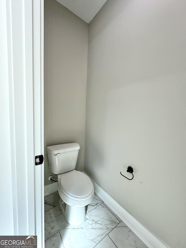 bathroom with marble finish floor, toilet, and baseboards