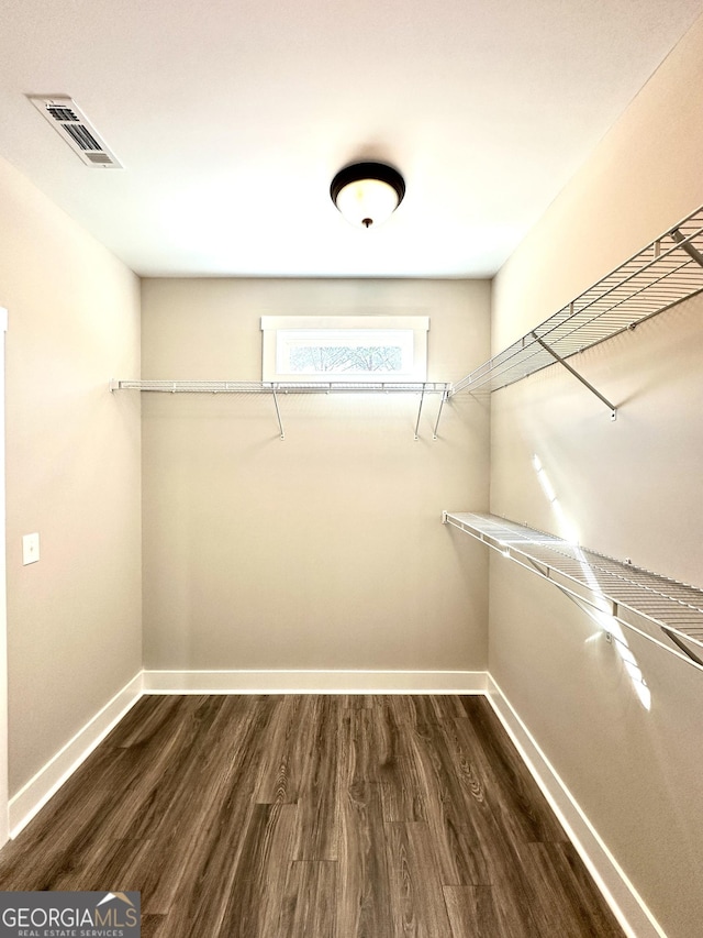 walk in closet with dark wood finished floors and visible vents