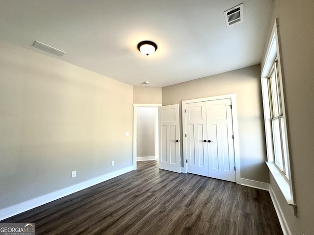 unfurnished bedroom with dark wood finished floors, visible vents, and baseboards