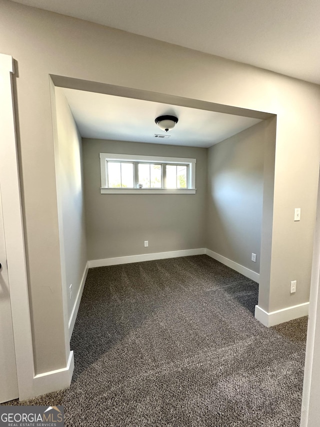 empty room with carpet, visible vents, and baseboards