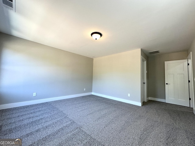 unfurnished room featuring dark colored carpet, visible vents, and baseboards