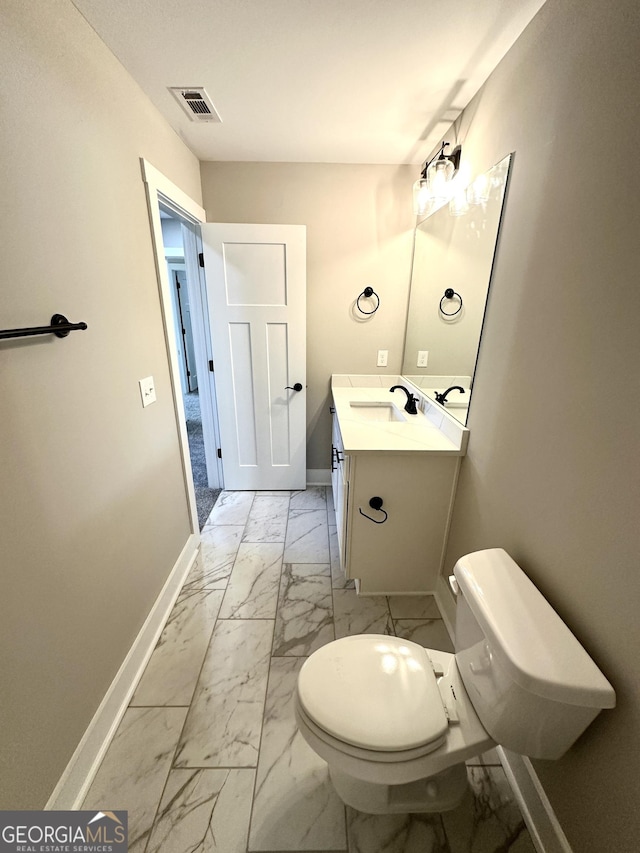 bathroom featuring toilet, vanity, visible vents, baseboards, and marble finish floor