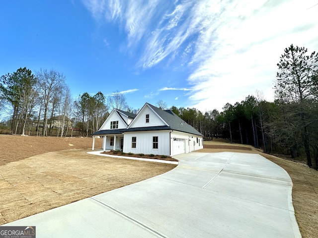 modern farmhouse style home with covered porch, concrete driveway, board and batten siding, and an attached garage