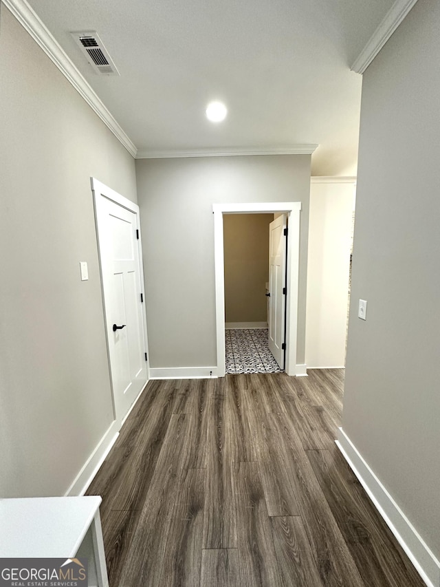 corridor with dark wood-style flooring, visible vents, crown molding, and baseboards