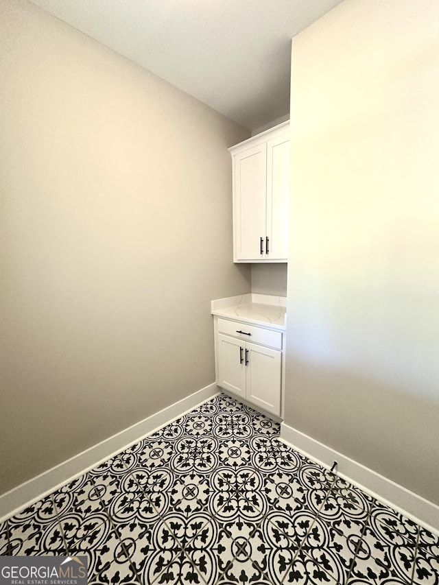 laundry area with baseboards and tile patterned floors