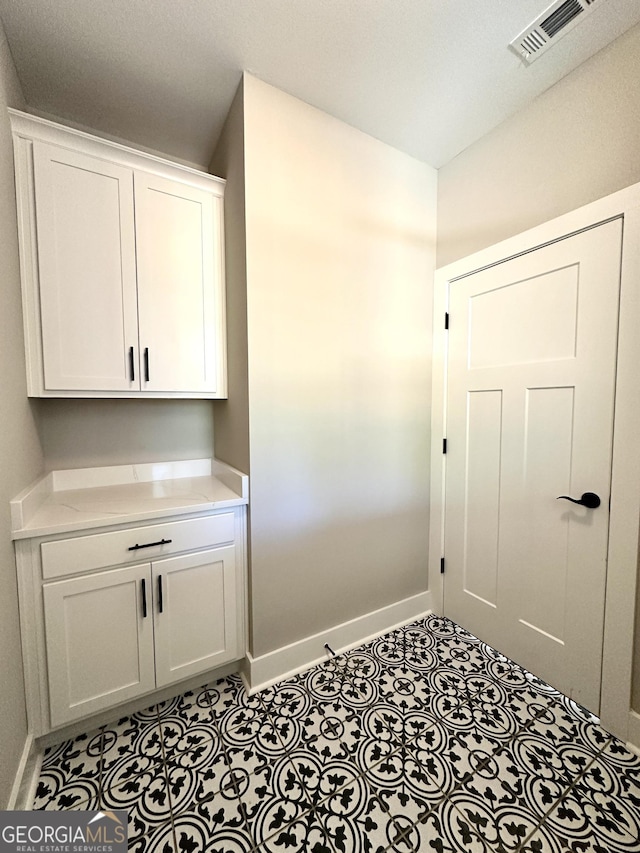 interior space featuring light tile patterned floors, visible vents, and baseboards