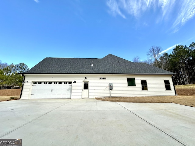 exterior space with concrete driveway, a shingled roof, and an attached garage