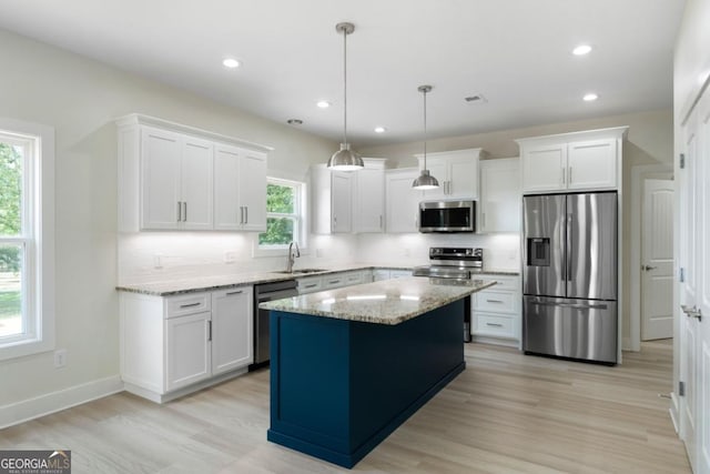 kitchen with white cabinetry, a kitchen island, a healthy amount of sunlight, and appliances with stainless steel finishes