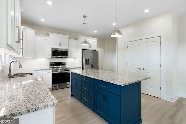 kitchen with a center island, white cabinets, blue cabinets, decorative light fixtures, and stainless steel appliances