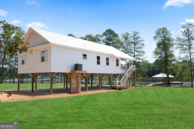 rear view of property featuring a lawn and central air condition unit