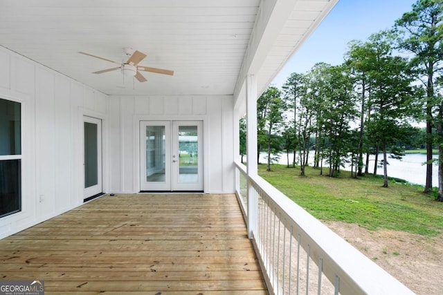 wooden deck with ceiling fan, a water view, and french doors