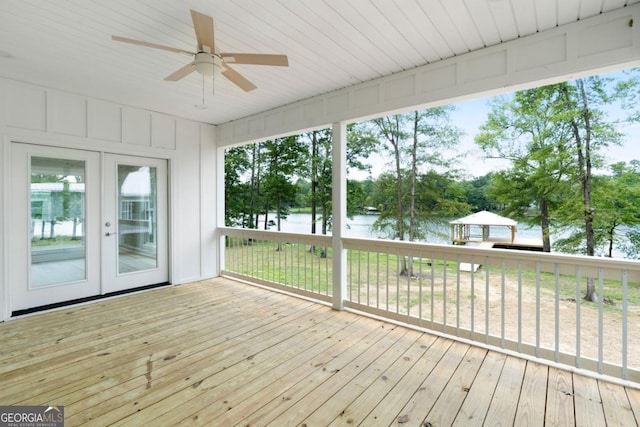 unfurnished sunroom featuring ceiling fan, french doors, and a water view