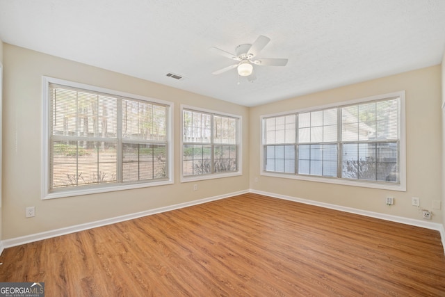 spare room featuring wood-type flooring, plenty of natural light, and ceiling fan