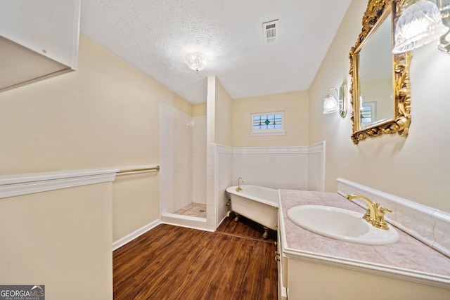 bathroom with vanity, a textured ceiling, hardwood / wood-style flooring, and plus walk in shower