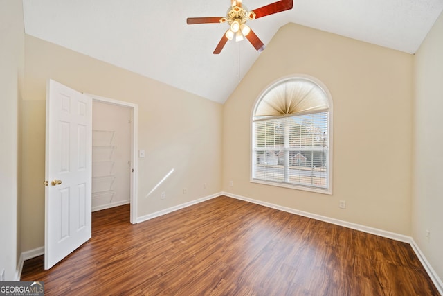 empty room with ceiling fan, dark hardwood / wood-style flooring, and vaulted ceiling