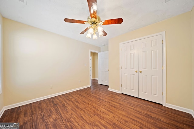 unfurnished bedroom with dark hardwood / wood-style floors, ceiling fan, and a closet