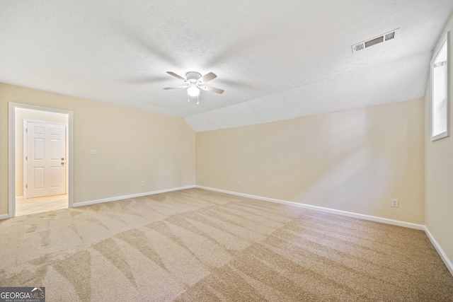 carpeted spare room featuring ceiling fan, a textured ceiling, and vaulted ceiling