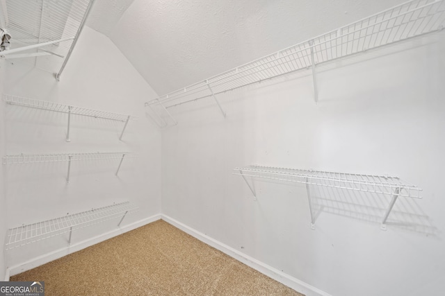 walk in closet with carpet flooring and vaulted ceiling