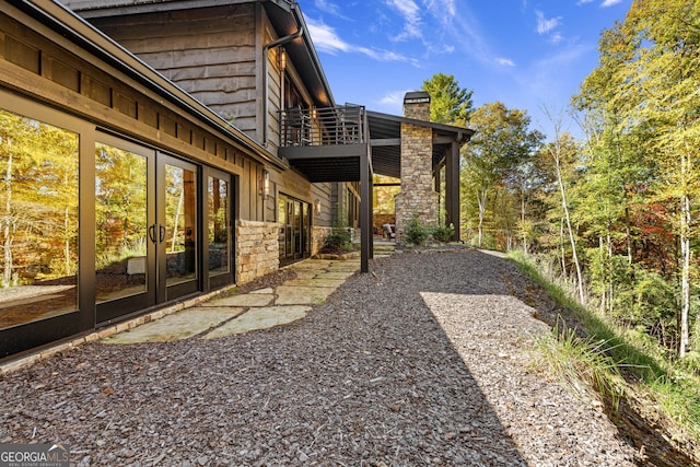 view of yard with french doors and a balcony