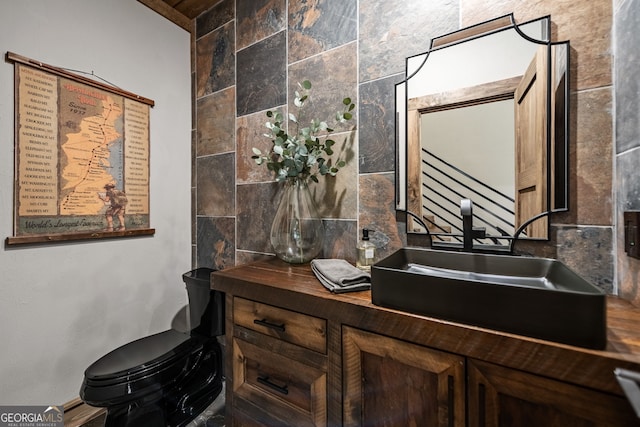 bathroom featuring vanity, toilet, decorative backsplash, and tile walls