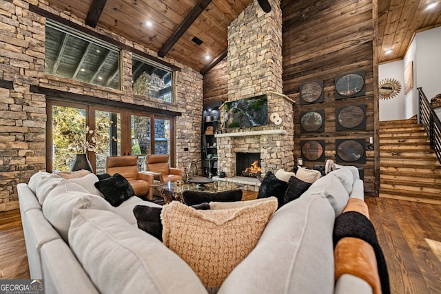 living room with hardwood / wood-style floors, wooden ceiling, high vaulted ceiling, a stone fireplace, and beamed ceiling