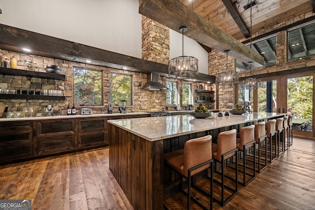 bar featuring beamed ceiling, a healthy amount of sunlight, and wall chimney range hood