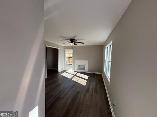 unfurnished living room featuring ceiling fan and dark hardwood / wood-style flooring