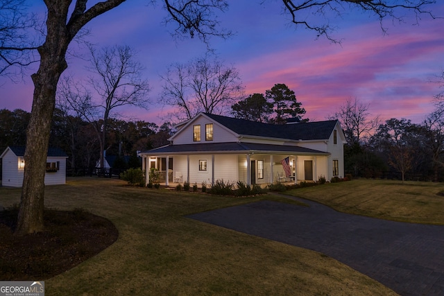 view of front of property featuring a lawn, an outbuilding, and covered porch