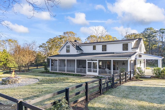 farmhouse with a front lawn, an outdoor fire pit, and a sunroom