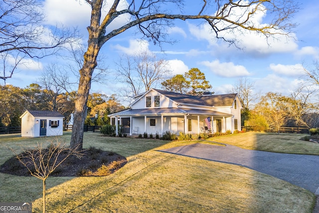 view of front of house featuring an outbuilding, a porch, and a front yard