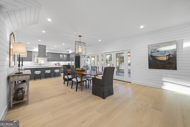 dining area featuring wooden walls, french doors, light hardwood / wood-style floors, and sink