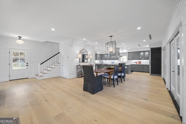 dining area featuring light hardwood / wood-style floors, an inviting chandelier, and ornamental molding