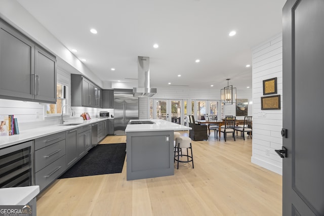 kitchen with exhaust hood, sink, a kitchen island, a kitchen bar, and stainless steel appliances