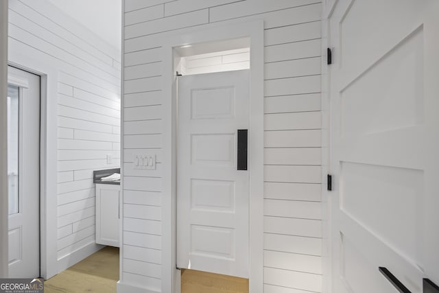 bathroom featuring wood-type flooring, vanity, and wood walls