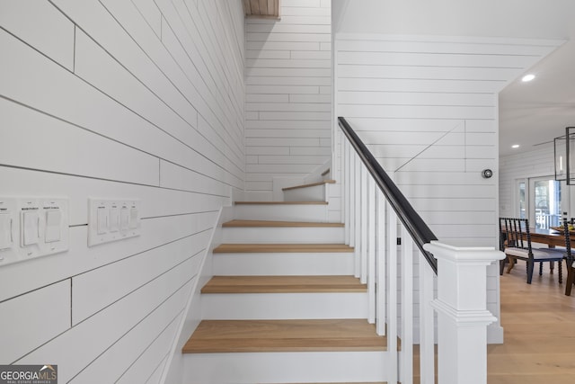 staircase with hardwood / wood-style floors and wood walls