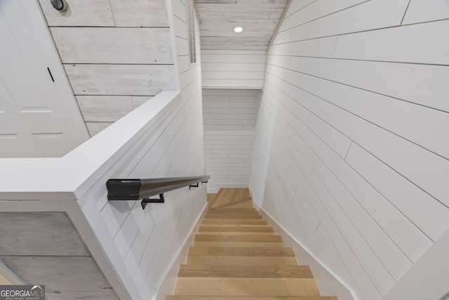 stairs featuring wood-type flooring and wood walls