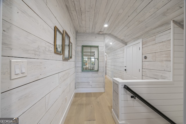 hallway with wood walls, lofted ceiling, wood ceiling, and light hardwood / wood-style flooring