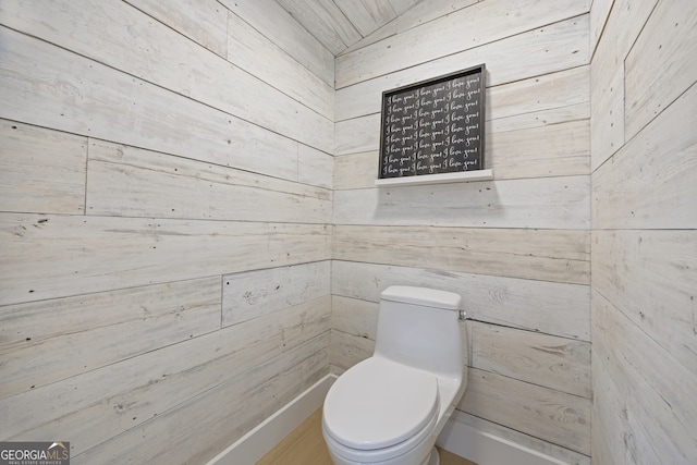 bathroom featuring toilet and wooden walls