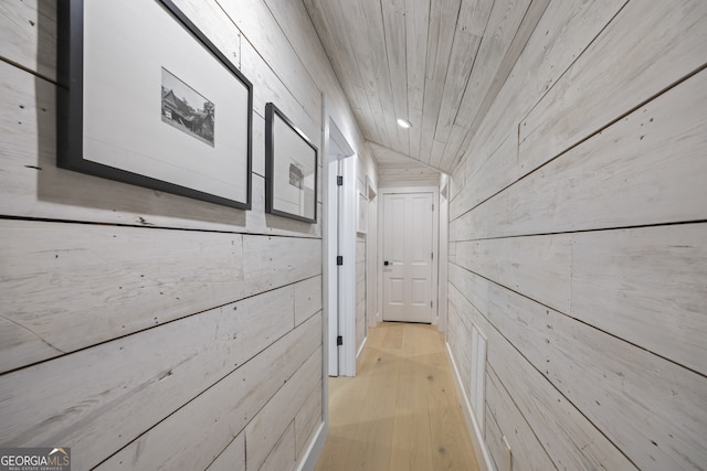 hall featuring wood walls, lofted ceiling, wood ceiling, and light hardwood / wood-style flooring