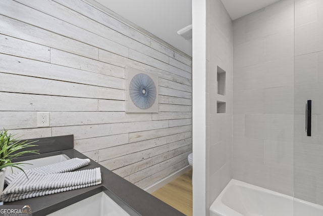 bathroom with hardwood / wood-style floors, wood walls, toilet, and a tub to relax in