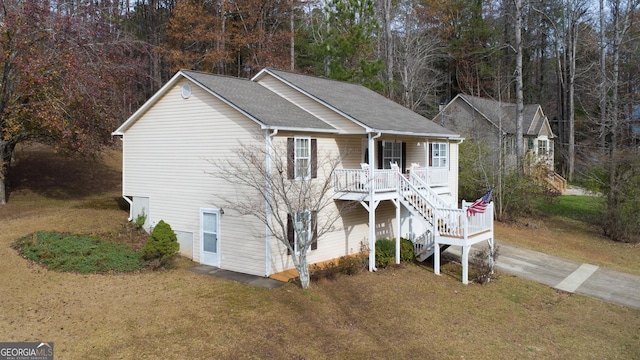 view of front facade with a front lawn, stairway, a porch, and a shingled roof